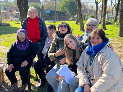 La imagen es una foto de un grupo de vecinos, en su mayoría mujeres, que forman parte de un grupo de garantia solidaria, en el Banquito del barrio La Carolina, en Ing. Allan, Florencio Varela, Buenos Aires.